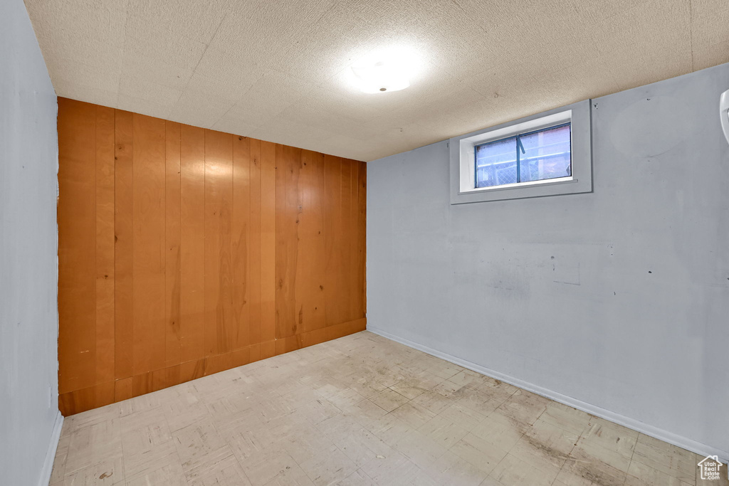Basement featuring tile patterned floors, wood walls, and baseboards