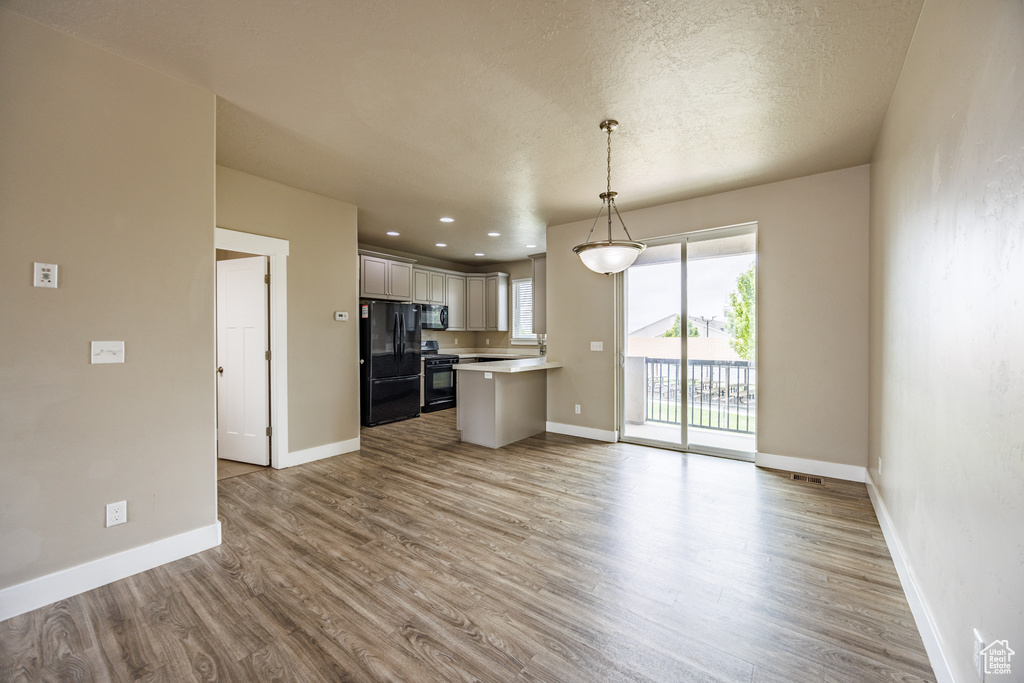 Kitchen with black appliances, light countertops, open floor plan, wood finished floors, and recessed lighting