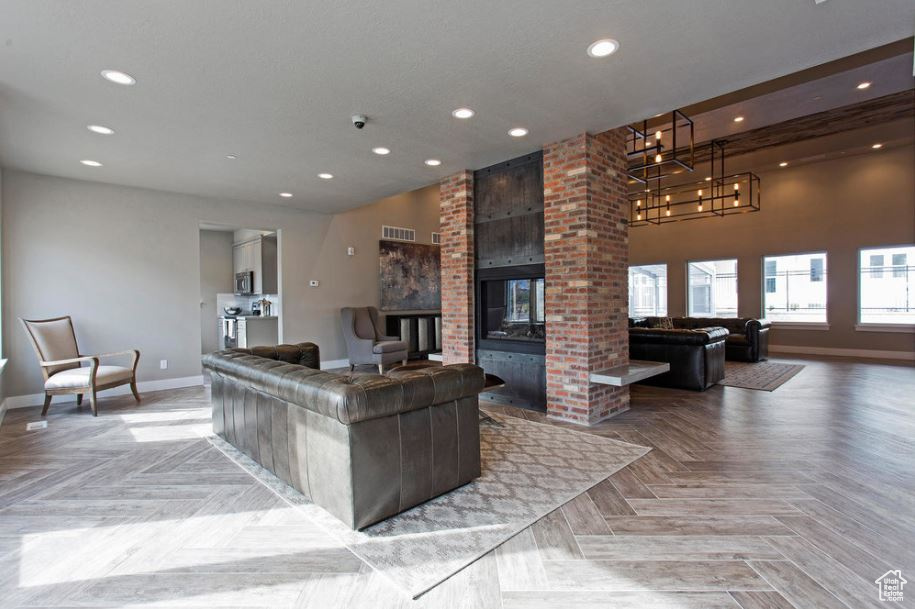 Living room featuring baseboards, recessed lighting, a fireplace, a high ceiling, and a chandelier