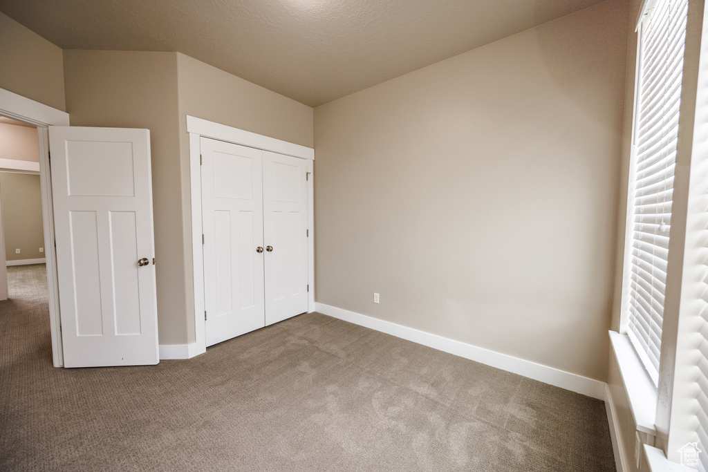 Unfurnished bedroom featuring carpet floors, baseboards, and a closet