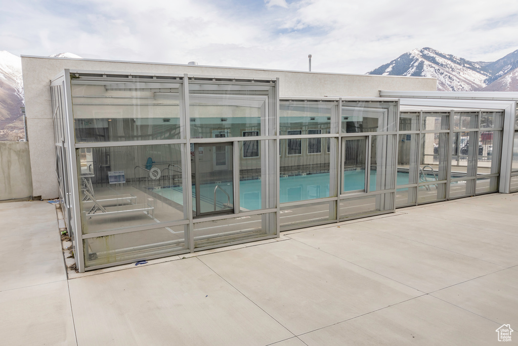 Community pool featuring a patio area, a mountain view, and a sunroom
