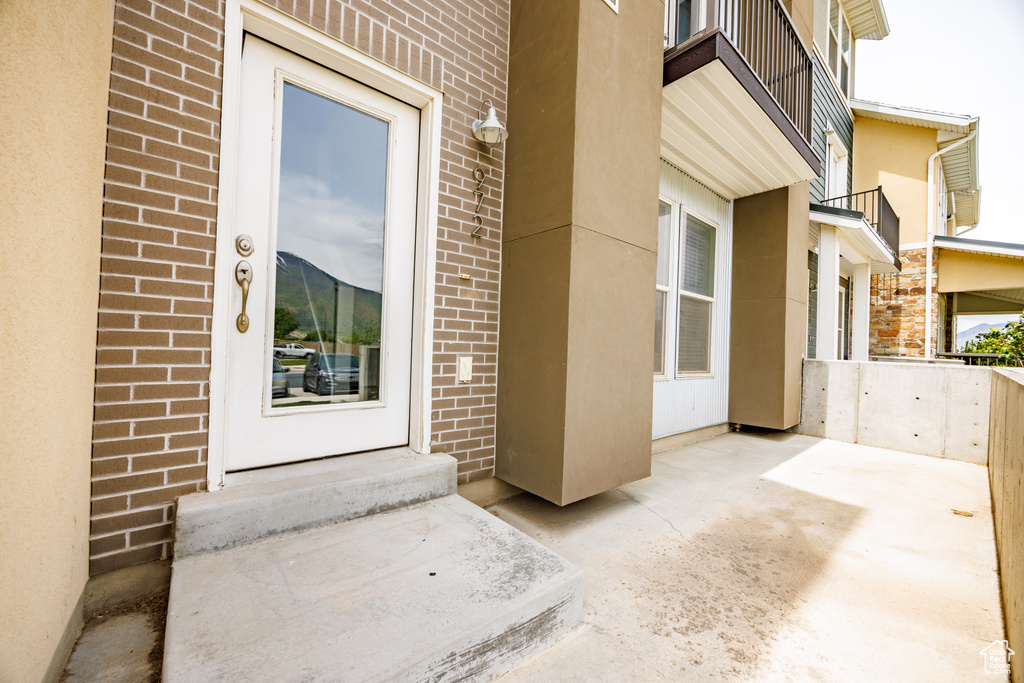 Doorway to property with brick siding, stucco siding, and a patio