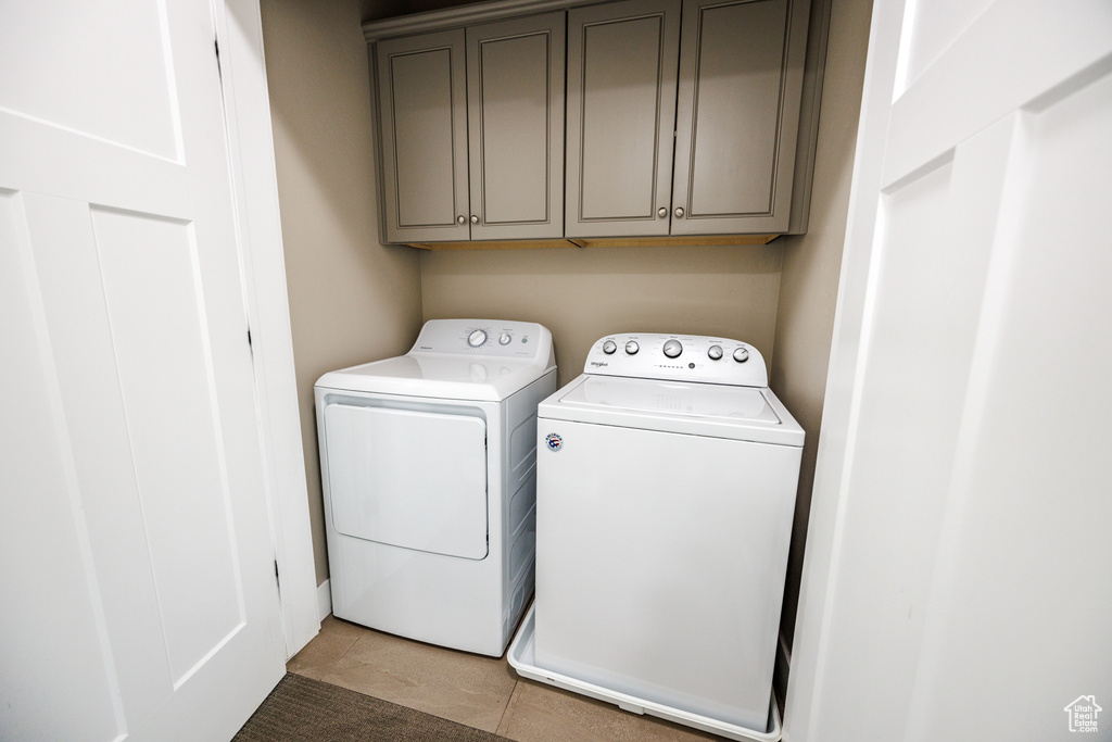 Laundry area with washer and clothes dryer, cabinet space, and light tile patterned floors