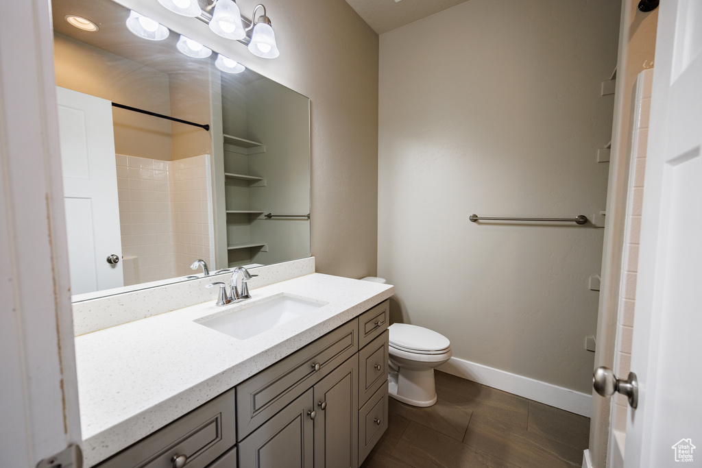 Bathroom with toilet, vanity, baseboards, a shower, and tile patterned flooring