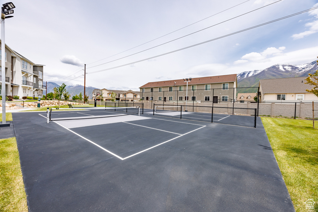 View of tennis court featuring a mountain view and fence
