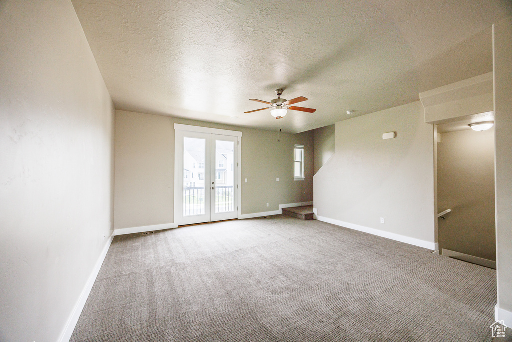 Spare room featuring ceiling fan, carpet, baseboards, a textured ceiling, and french doors