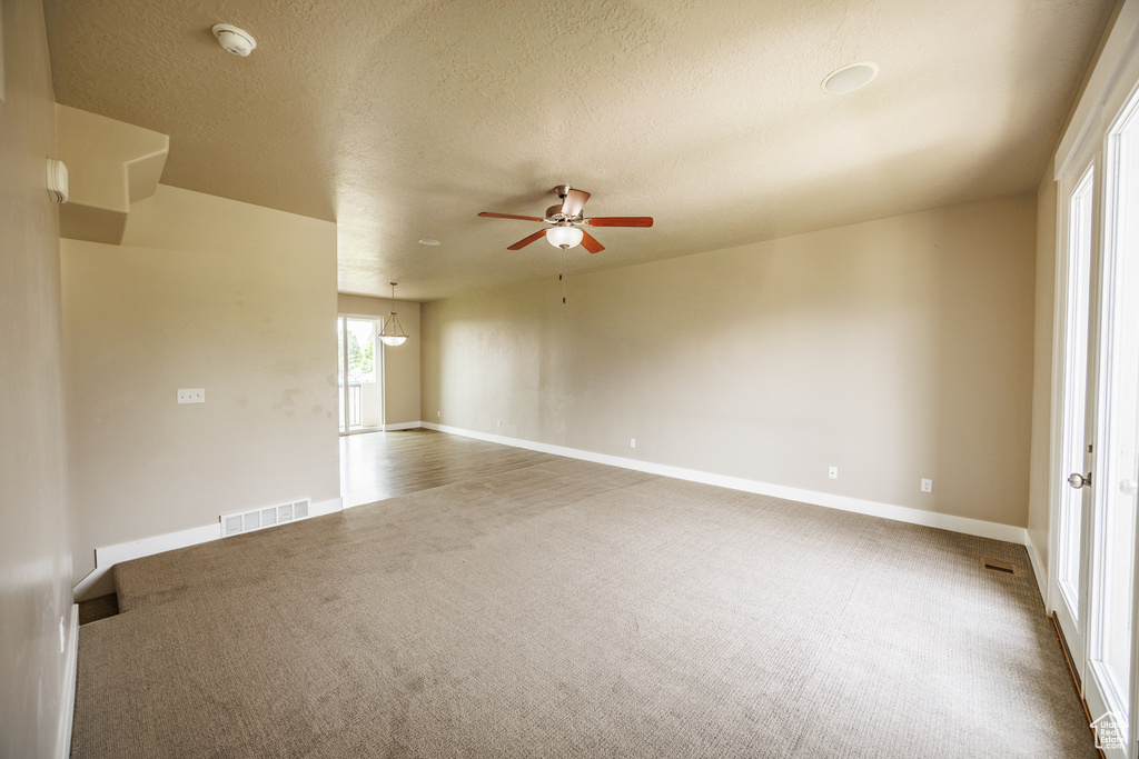 Spare room with carpet flooring, ceiling fan, baseboards, and a textured ceiling