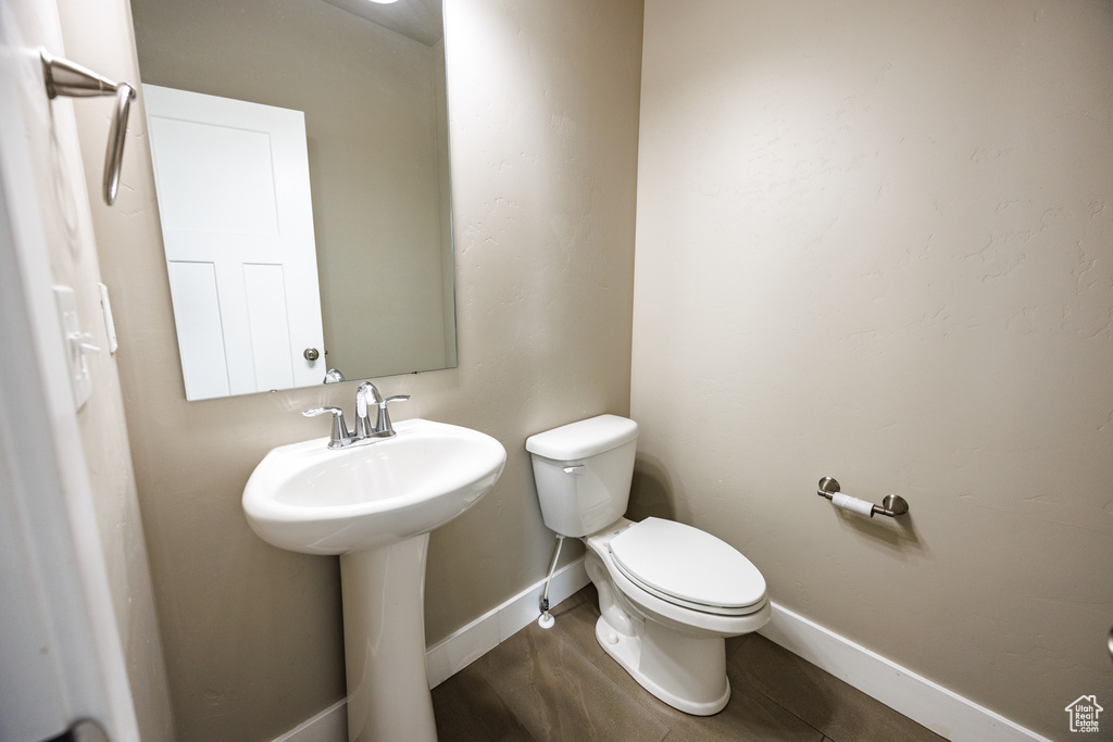 Bathroom featuring toilet, baseboards, and a sink