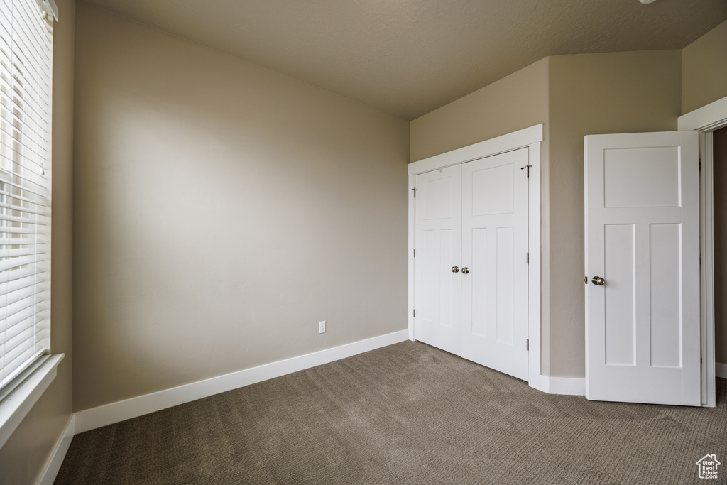 Unfurnished bedroom featuring carpet floors, baseboards, and a closet