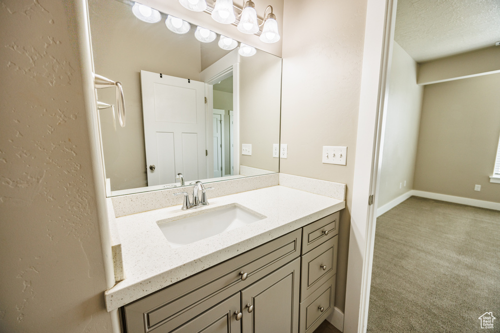 Bathroom featuring vanity, baseboards, and a textured ceiling