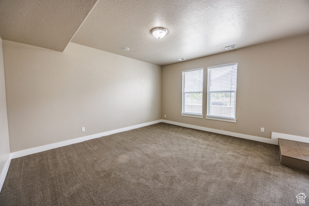 Unfurnished room with carpet flooring, a textured ceiling, and baseboards