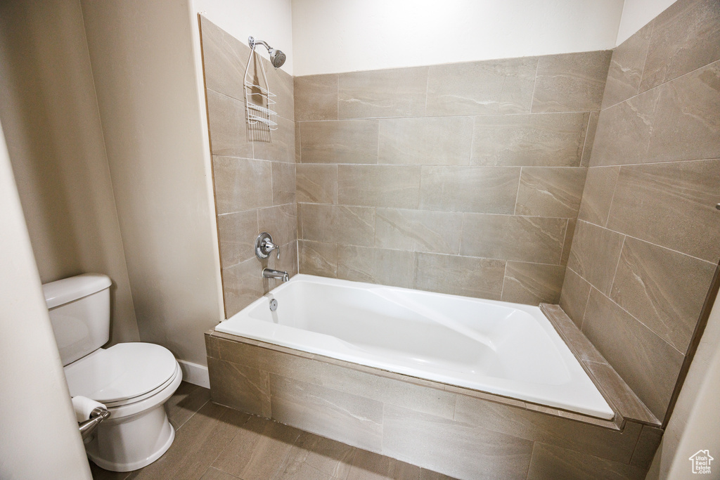 Bathroom featuring toilet, tiled shower / bath combo, and wood finished floors