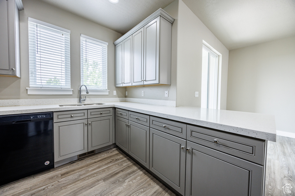 Kitchen with dishwasher, a sink, gray cabinetry, and a peninsula