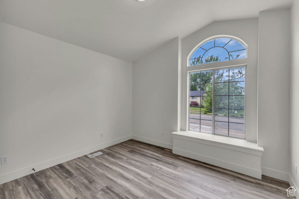Unfurnished room with lofted ceiling, wood finished floors, and baseboards