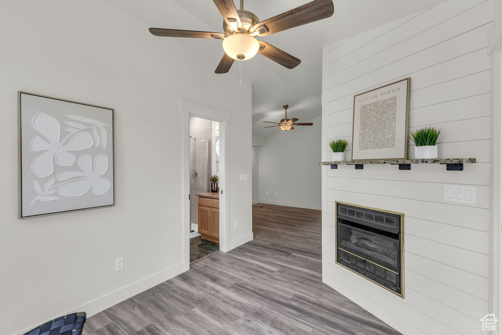 Unfurnished living room with a ceiling fan, baseboards, wood finished floors, and a glass covered fireplace
