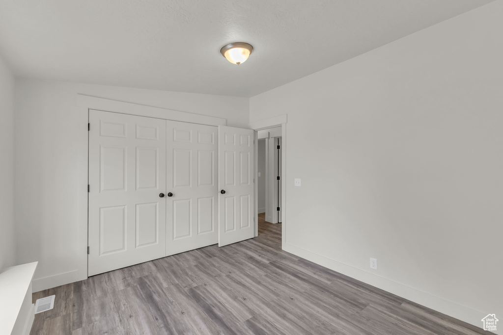 Unfurnished bedroom with wood finished floors, a closet, and baseboards
