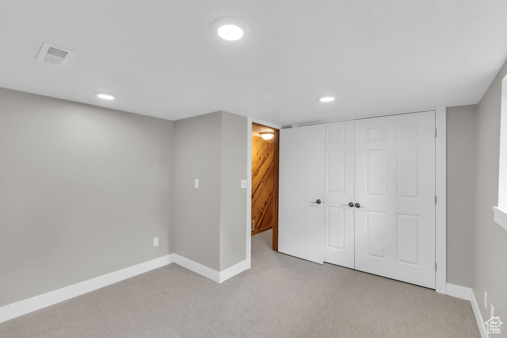 Finished below grade area with light colored carpet, recessed lighting, and baseboards