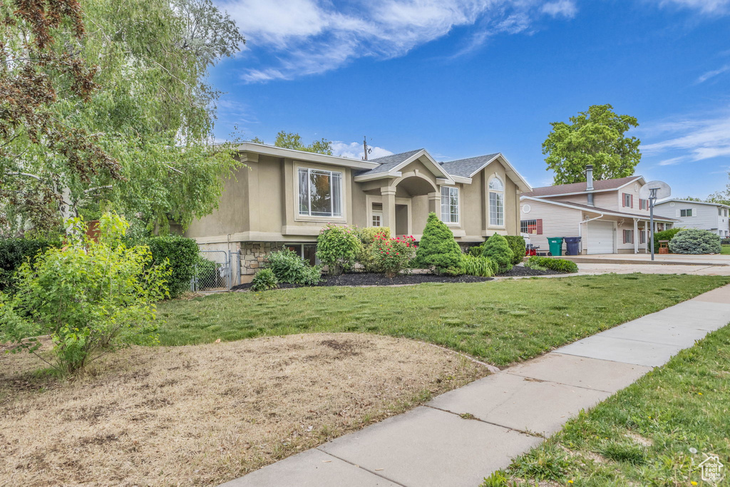 View of front of home featuring stucco siding, a front yard, and stone siding