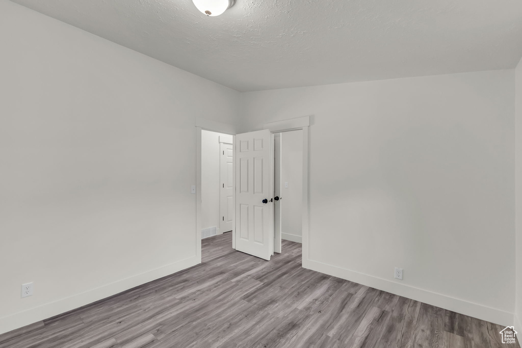 Spare room with baseboards, wood finished floors, and a textured ceiling