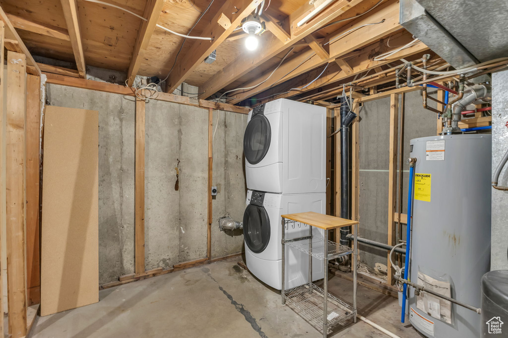 Unfinished below grade area featuring stacked washer / drying machine and water heater