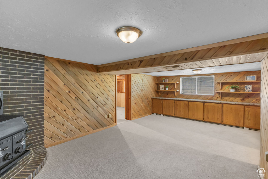 Bar area with wood walls, a wood stove, light carpet, and a textured ceiling