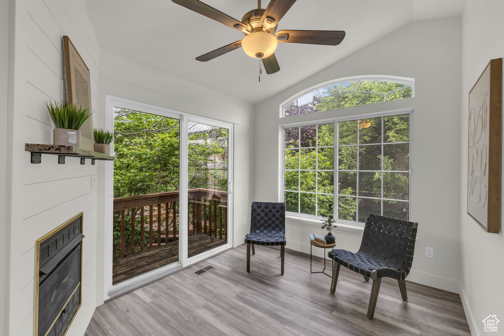 Sitting room with vaulted ceiling, plenty of natural light, baseboards, wood finished floors, and a glass covered fireplace