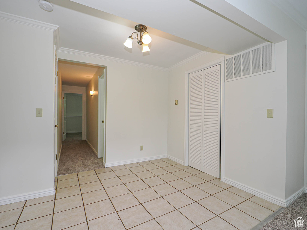 Unfurnished bedroom with a closet, baseboards, crown molding, and light tile patterned floors