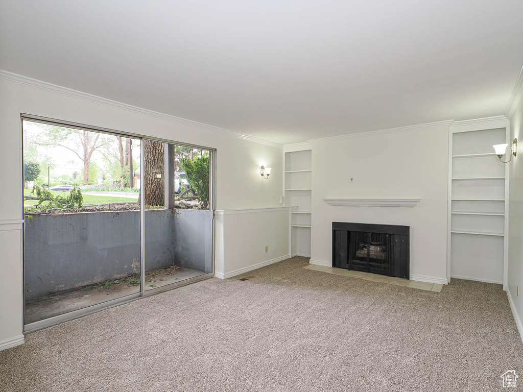 Unfurnished living room featuring crown molding, built in features, carpet floors, a fireplace with flush hearth, and baseboards