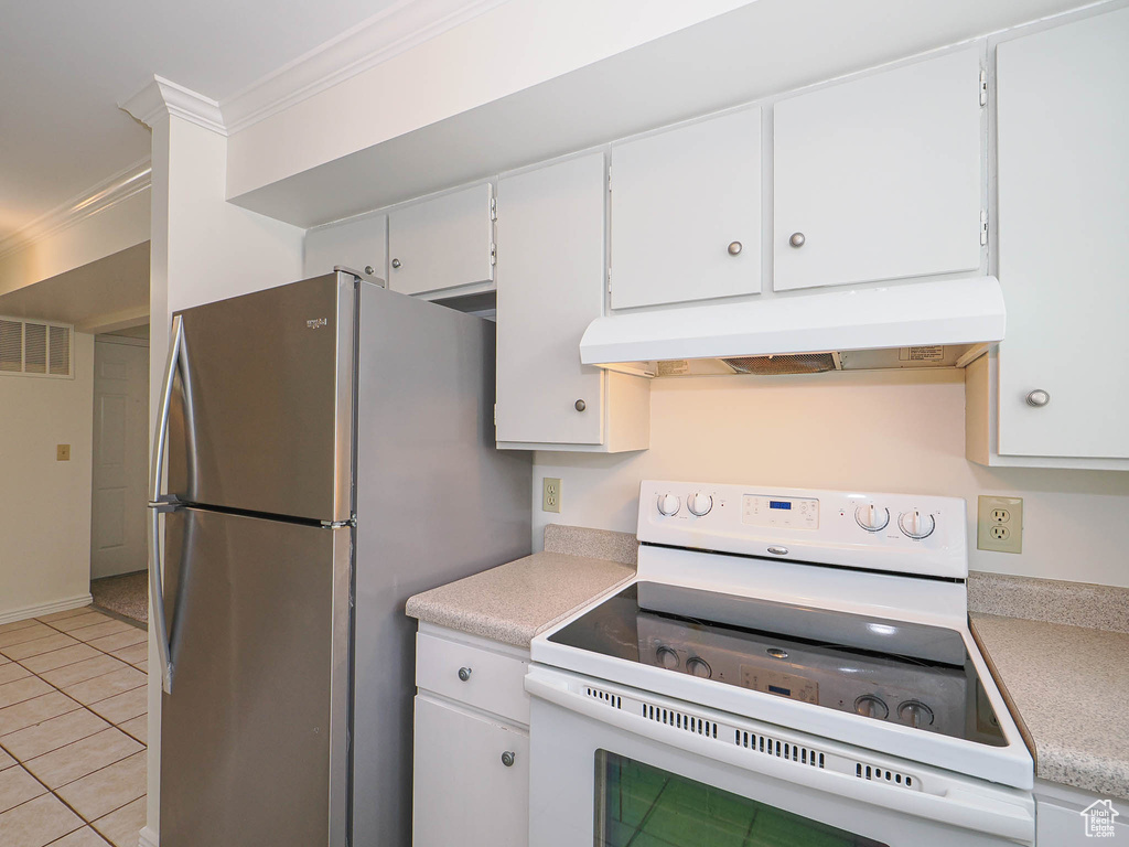 Kitchen featuring white electric range, under cabinet range hood, freestanding refrigerator, light countertops, and ornamental molding