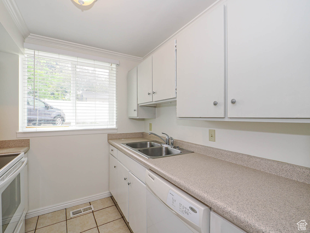 Kitchen with a sink, white appliances, white cabinets, crown molding, and light countertops