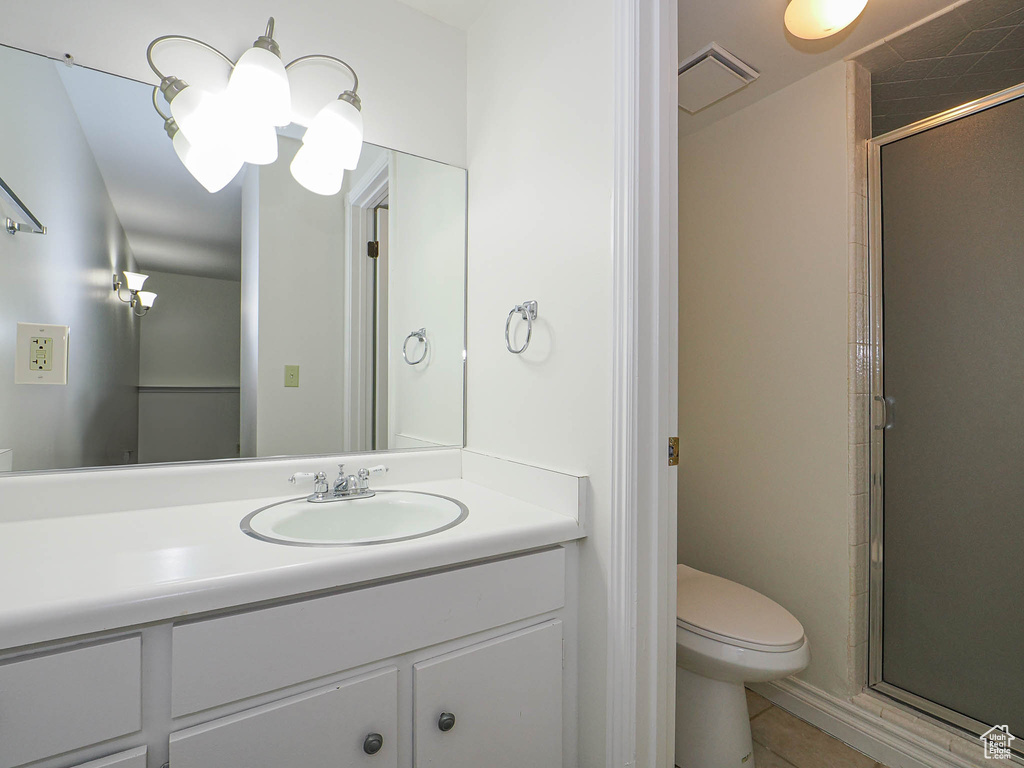 Bathroom featuring toilet, a stall shower, tile patterned floors, and vanity