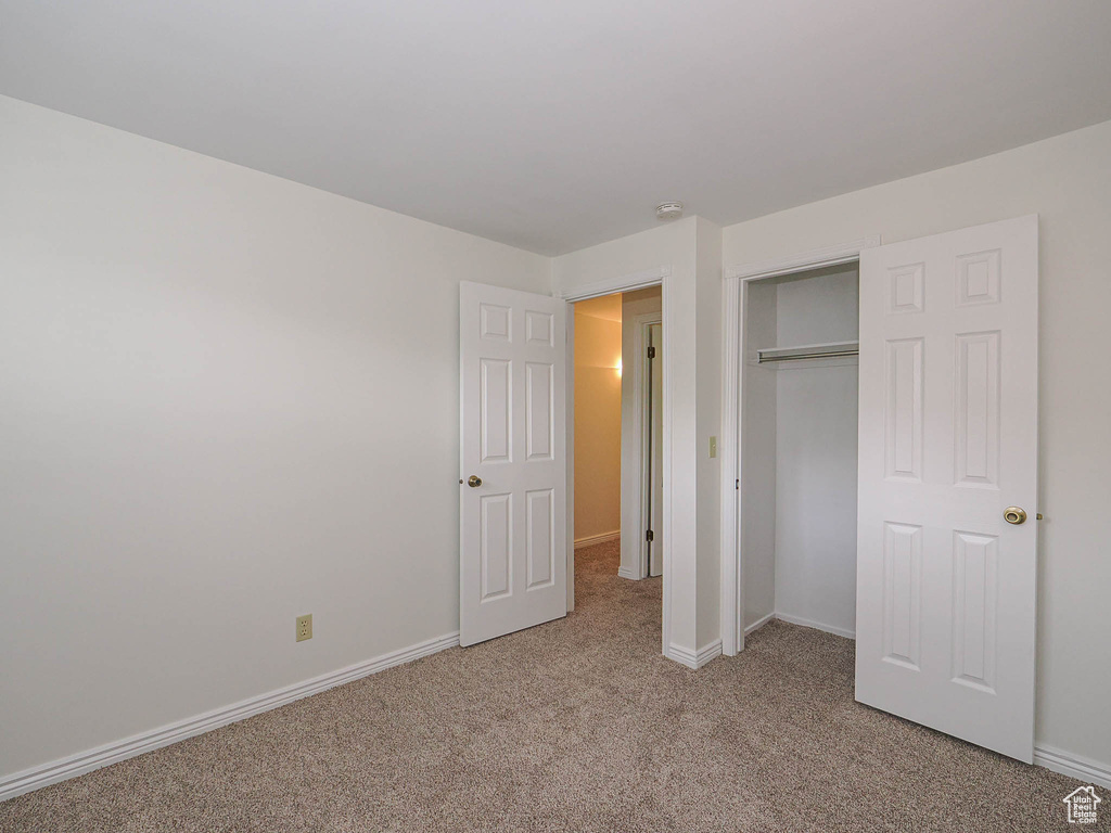 Unfurnished bedroom with light colored carpet, baseboards, and a closet