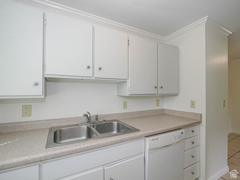 Kitchen with dishwasher, a sink, light tile patterned floors, light countertops, and white cabinetry
