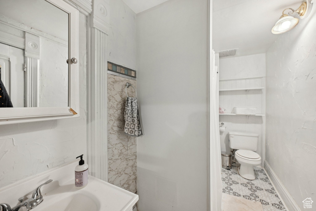 Bathroom with toilet, a sink, and tile patterned flooring