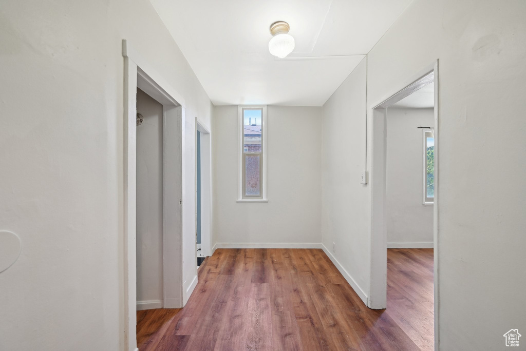 Hallway with plenty of natural light, wood finished floors, and baseboards
