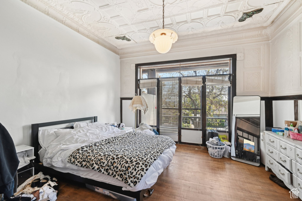 Bedroom featuring an ornate ceiling, wood finished floors, and ornamental molding
