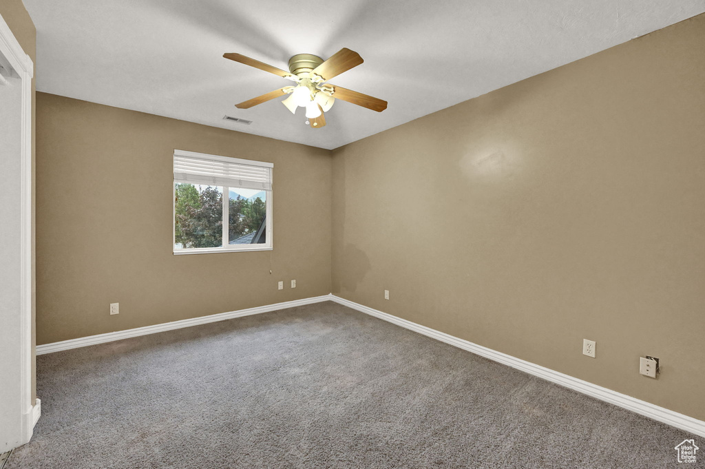 Carpeted empty room with baseboards and ceiling fan