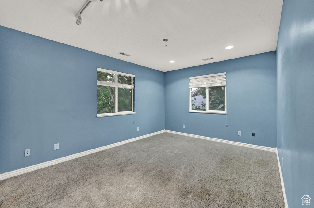 Carpeted empty room featuring plenty of natural light, baseboards, track lighting, and recessed lighting