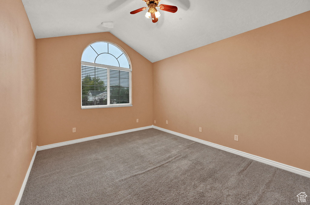Unfurnished room featuring ceiling fan, lofted ceiling, carpet floors, and baseboards
