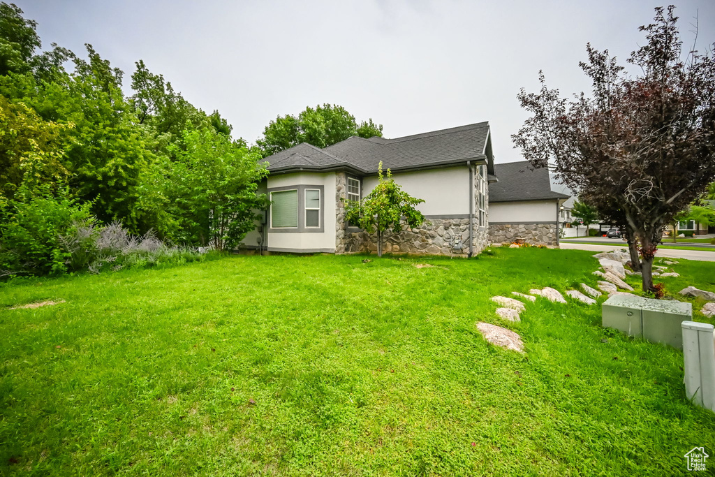 View of home's exterior with stucco siding, stone siding, and a lawn
