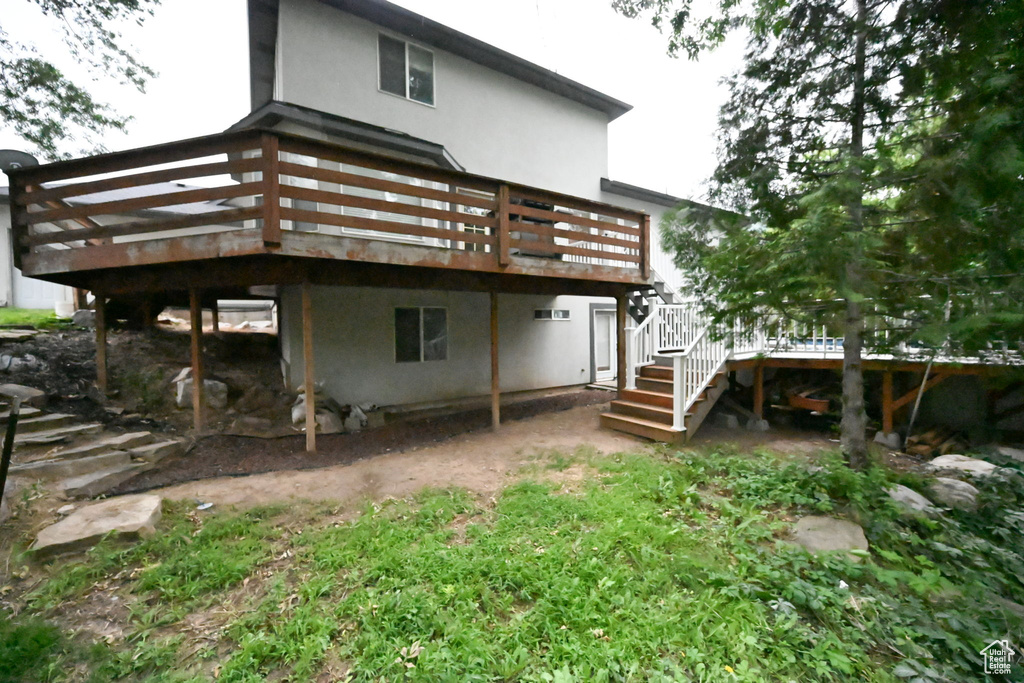 Back of property featuring a deck, stucco siding, and stairs