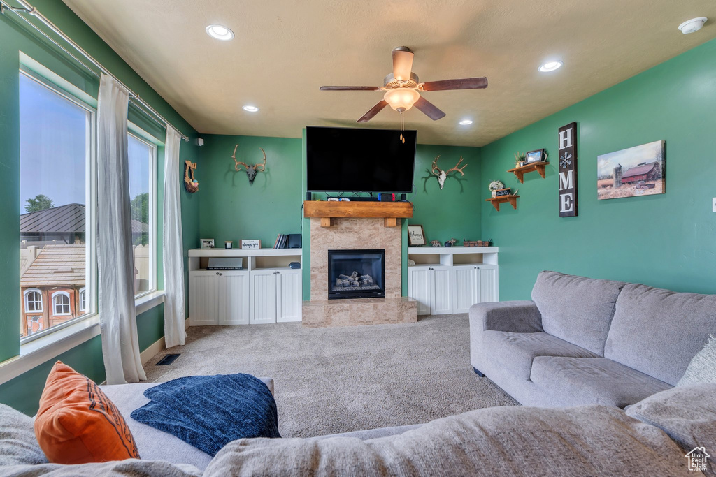 Carpeted living room featuring ceiling fan, recessed lighting, a stone fireplace, and baseboards