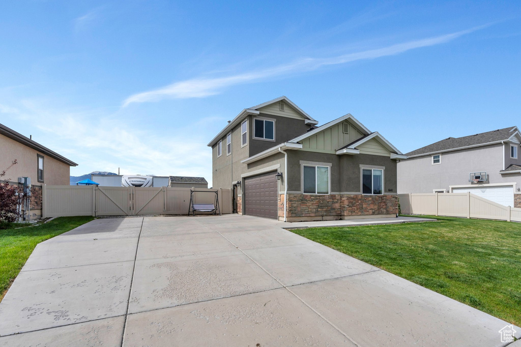 View of front of property with a gate, concrete driveway, stone siding, stucco siding, and an attached garage