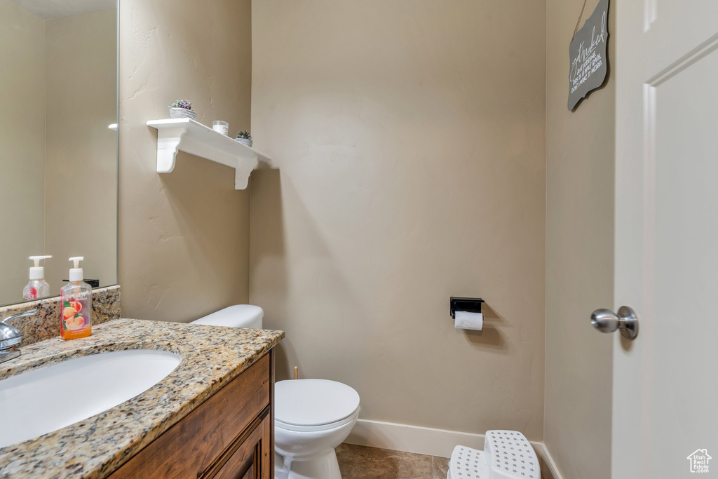 Bathroom featuring vanity, toilet, and baseboards