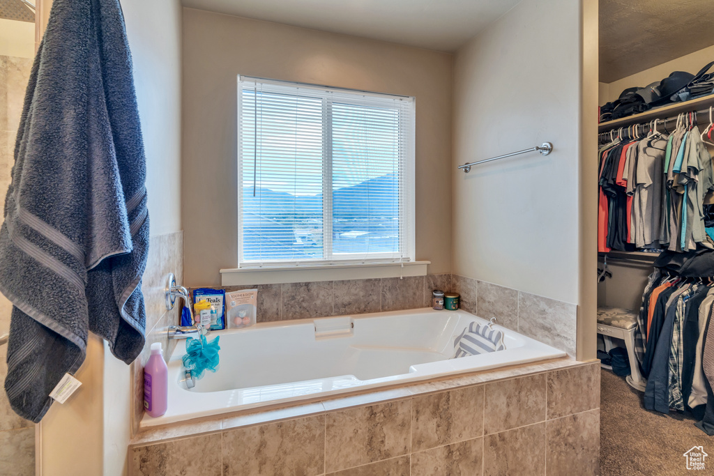 Full bath featuring plenty of natural light, a walk in closet, and a bath