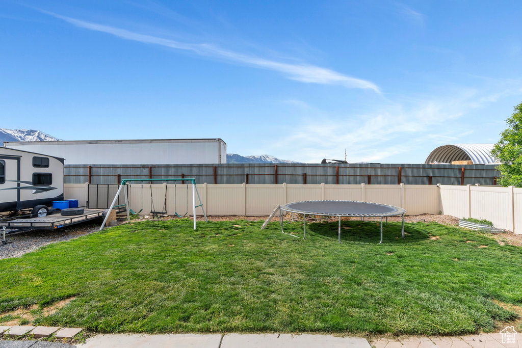 View of yard with a trampoline and a playground