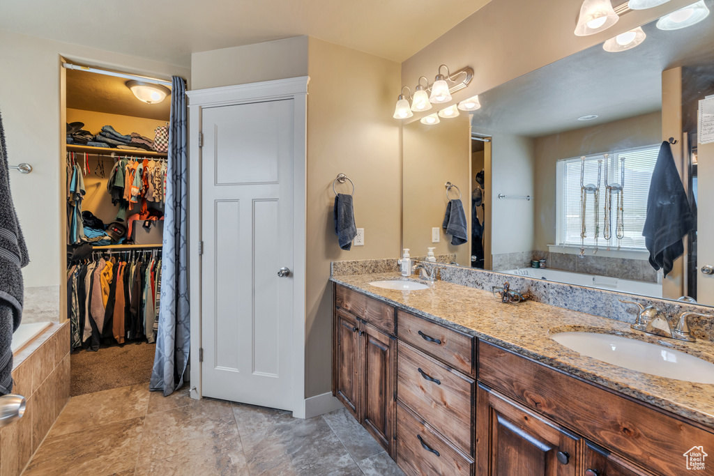 Full bath with double vanity, a walk in closet, and a tub to relax in