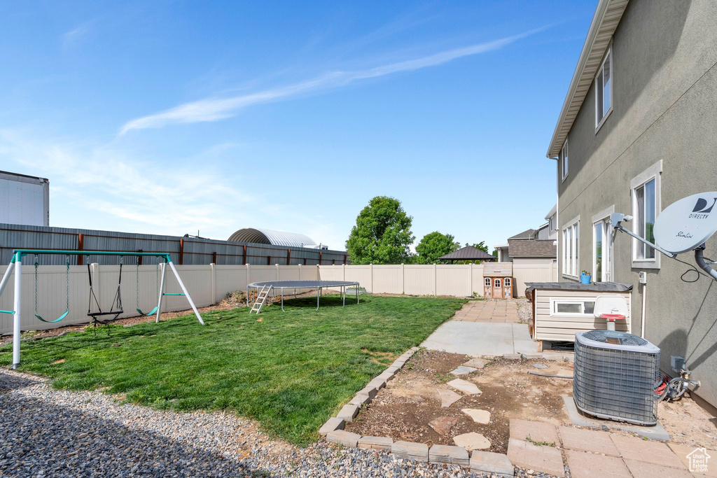 View of yard with a trampoline, a playground, central AC unit, and a patio