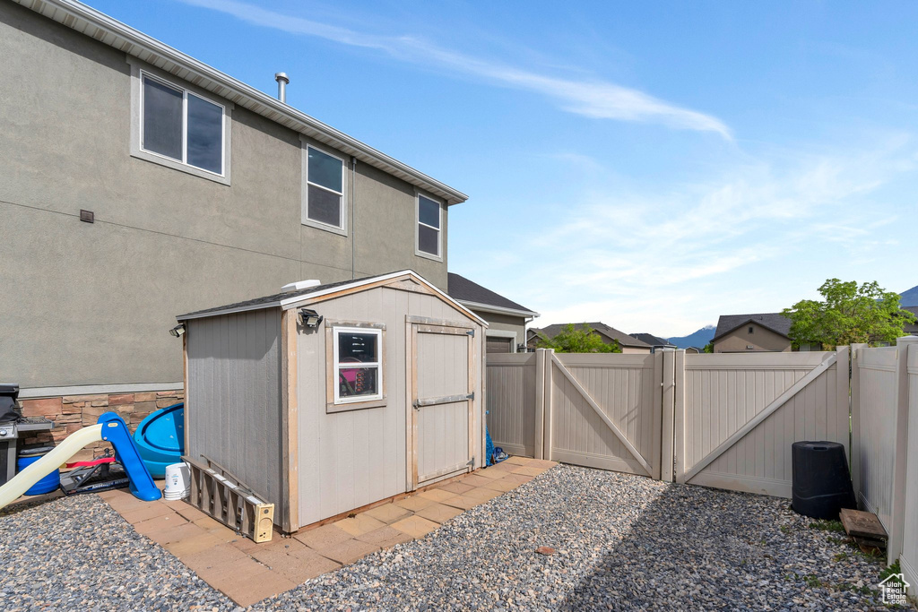 View of patio with a gate, a storage shed, an outbuilding, and fence