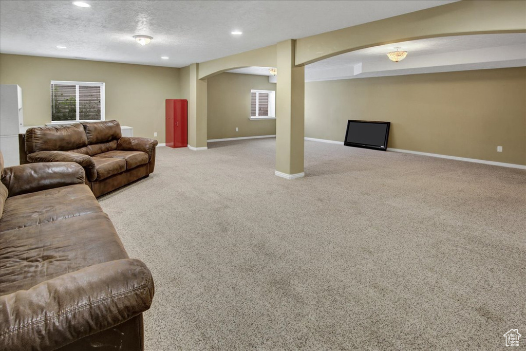 Carpeted living room with arched walkways, baseboards, and recessed lighting